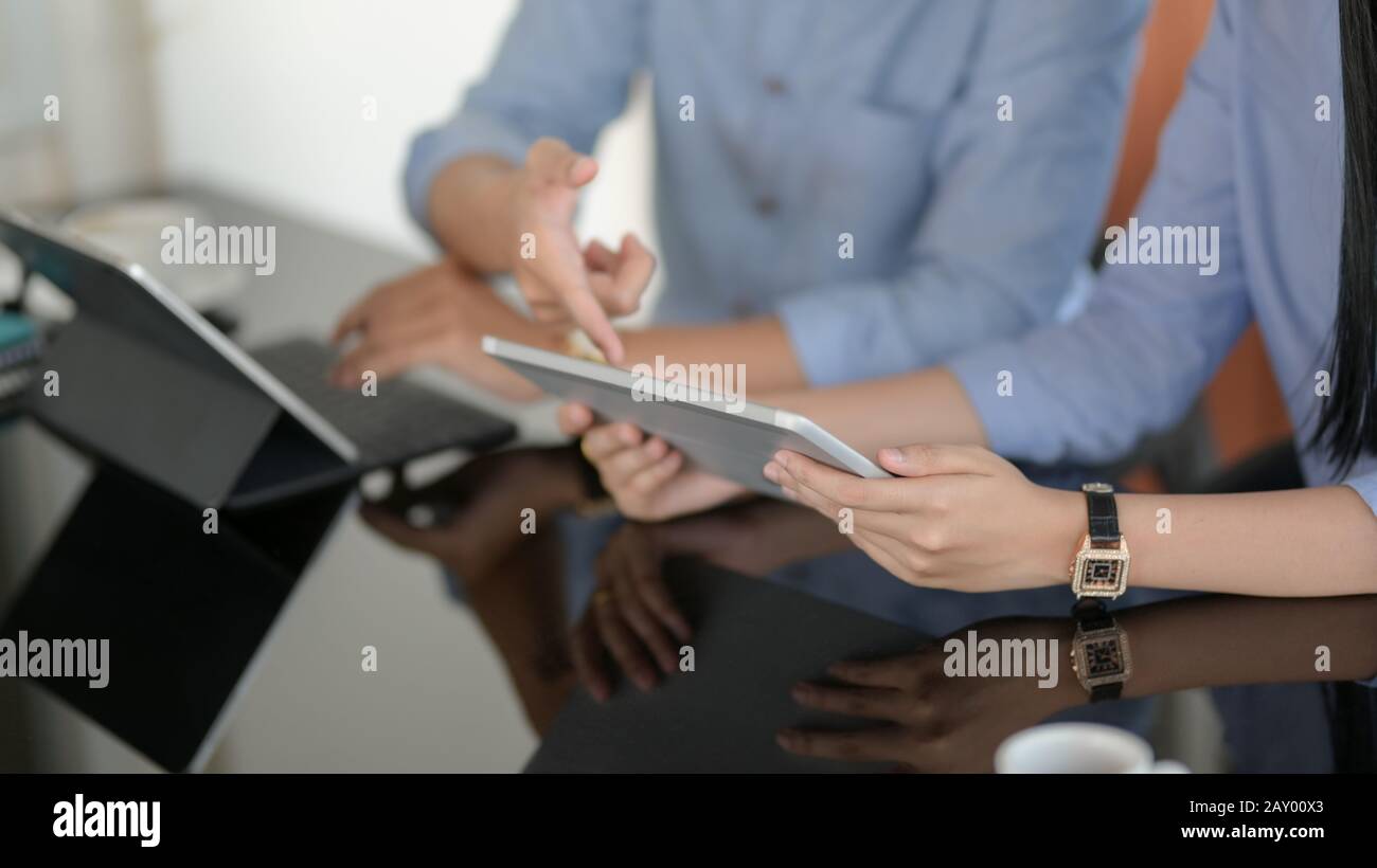 Ein Foto von Geschäftsleuten, die sich mit digitalen Tablets auf schwarzem Schreibtisch zu ihrem Projekt beraten Stockfoto