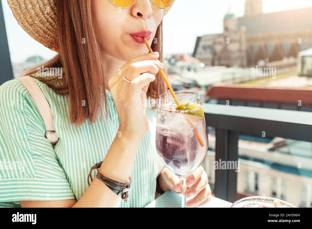 Nahaufnahme der asiatischen Frau, die Cocktail auf der Terrasse mit offener Bar auf dem Dach trinkt, mit großartigem Blick auf die Stadt Wien Stockfoto