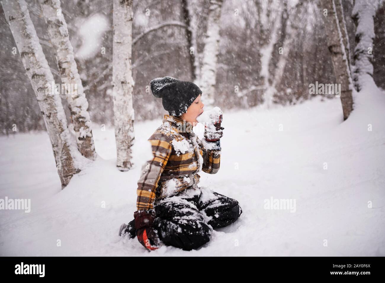 Junge sitzen draußen und essen Schnee, Wisconsin, USA Stockfoto