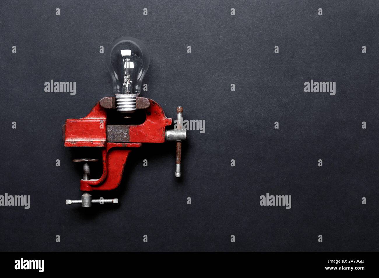 Glühlampe in mechanischer Handlaster auf grauem Hintergrund mit Kopierraum eingeklemmt. Kreatives Konzept Stockfoto