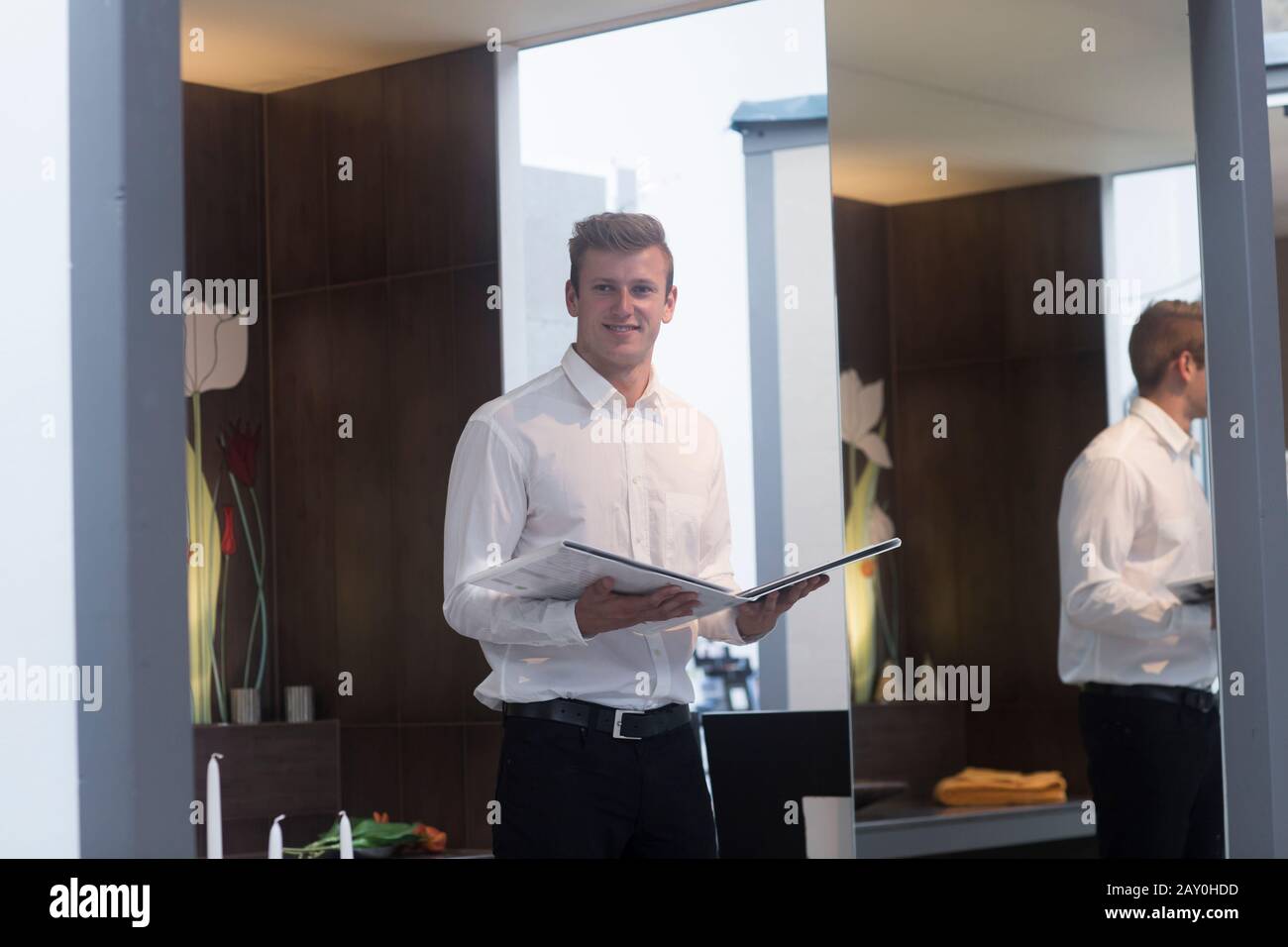 Lächelnder Verkäufer steht in einem Geschäft mit Verkaufsbroschüre, Deutschland Stockfoto
