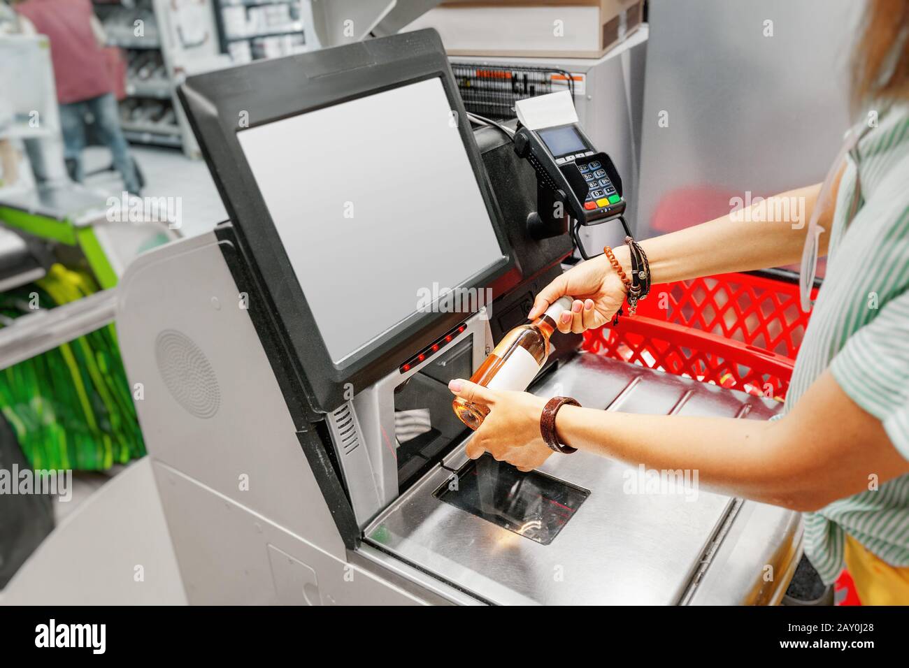 Girl-Kunde scannt eine Flasche Wein an der Selbstbedienungskontrolle im Supermarkt Stockfoto