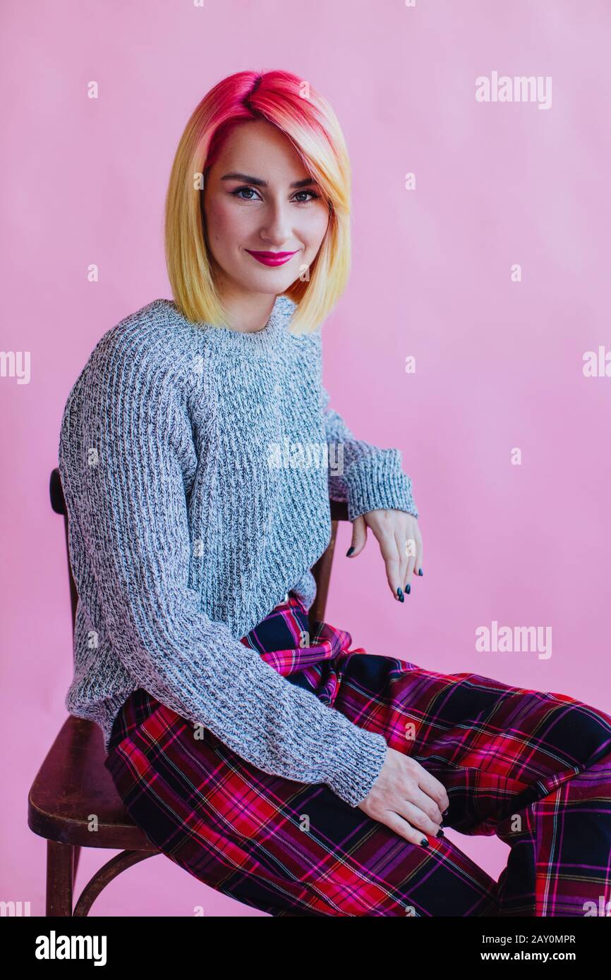 Porträt eines coolen Mädchens mit gefärbtem Haar, das auf einem Stuhl sitzt Stockfoto