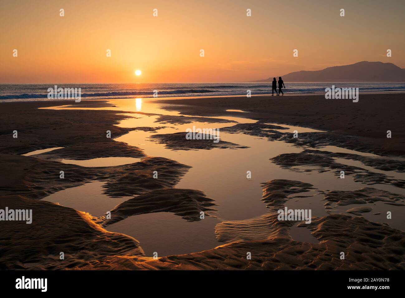 Silhouette zweier Frauen, die bei Sonnenuntergang am Strand spazieren, Tarifa, Cadiz, Andalusien, Spanien Stockfoto