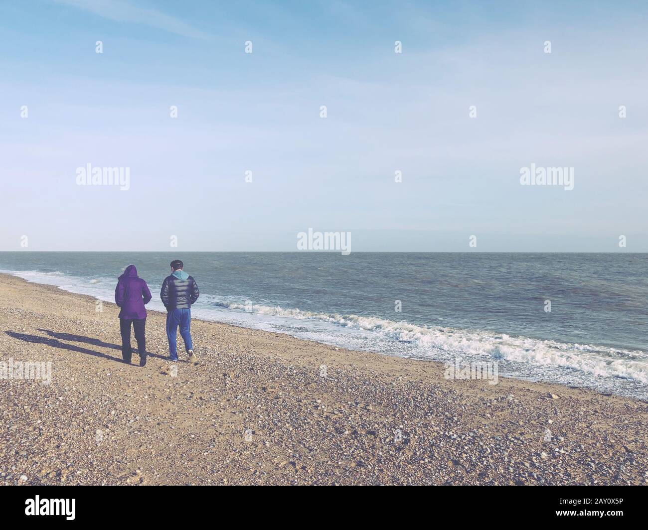 Zwei Personen, die im Winter am Strand spazieren, Aldeburgh, Suffolk, England, Großbritannien Stockfoto