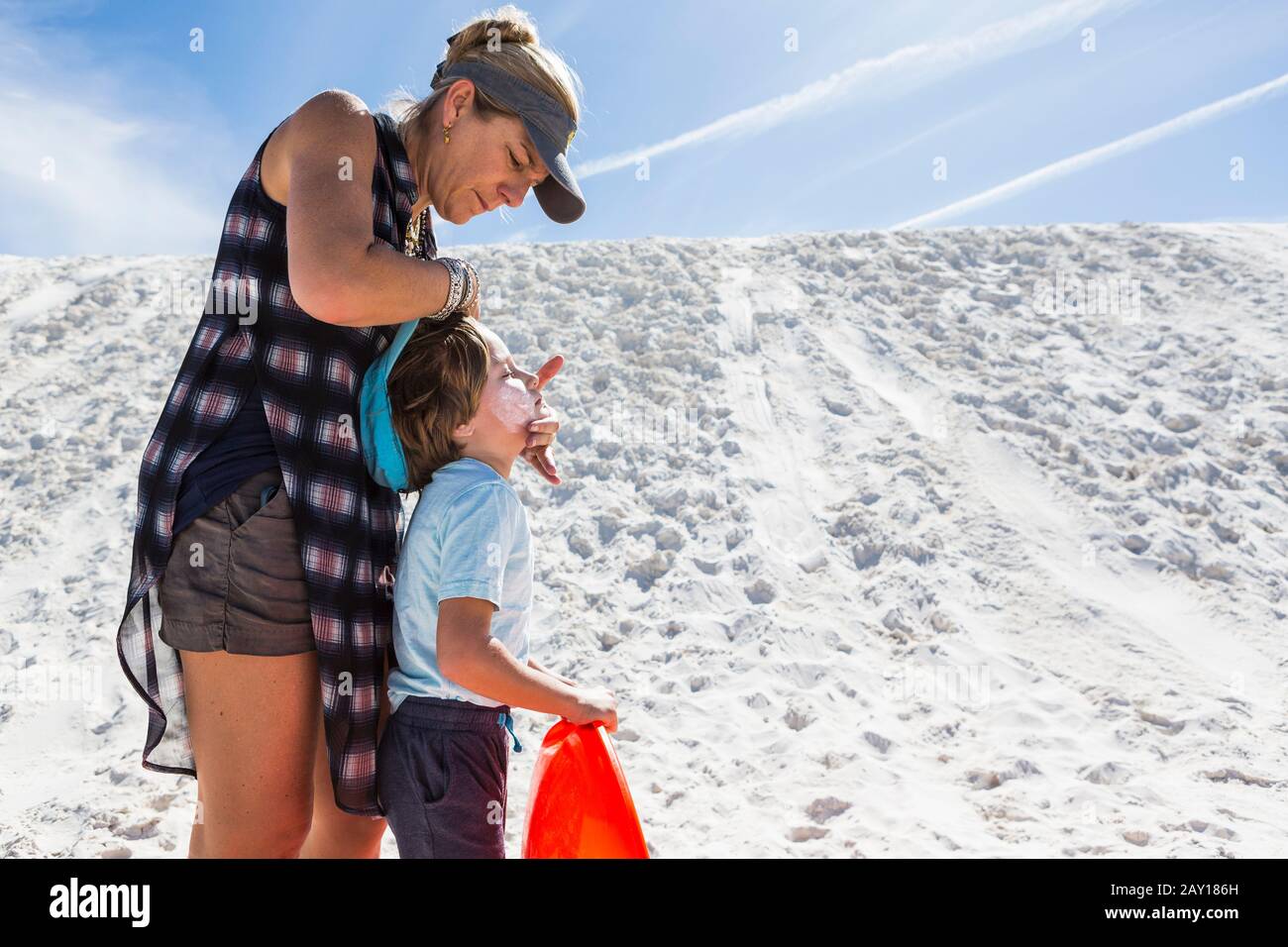 Mutter, die ihrem Kind einen Sonnenblock abhängt Stockfoto