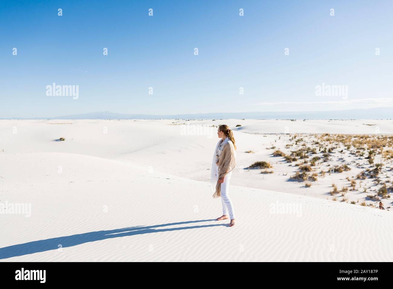 13 Jahre altes Mädchen, das auf einen weiten Freiraum von Sanddünen blickt. Stockfoto