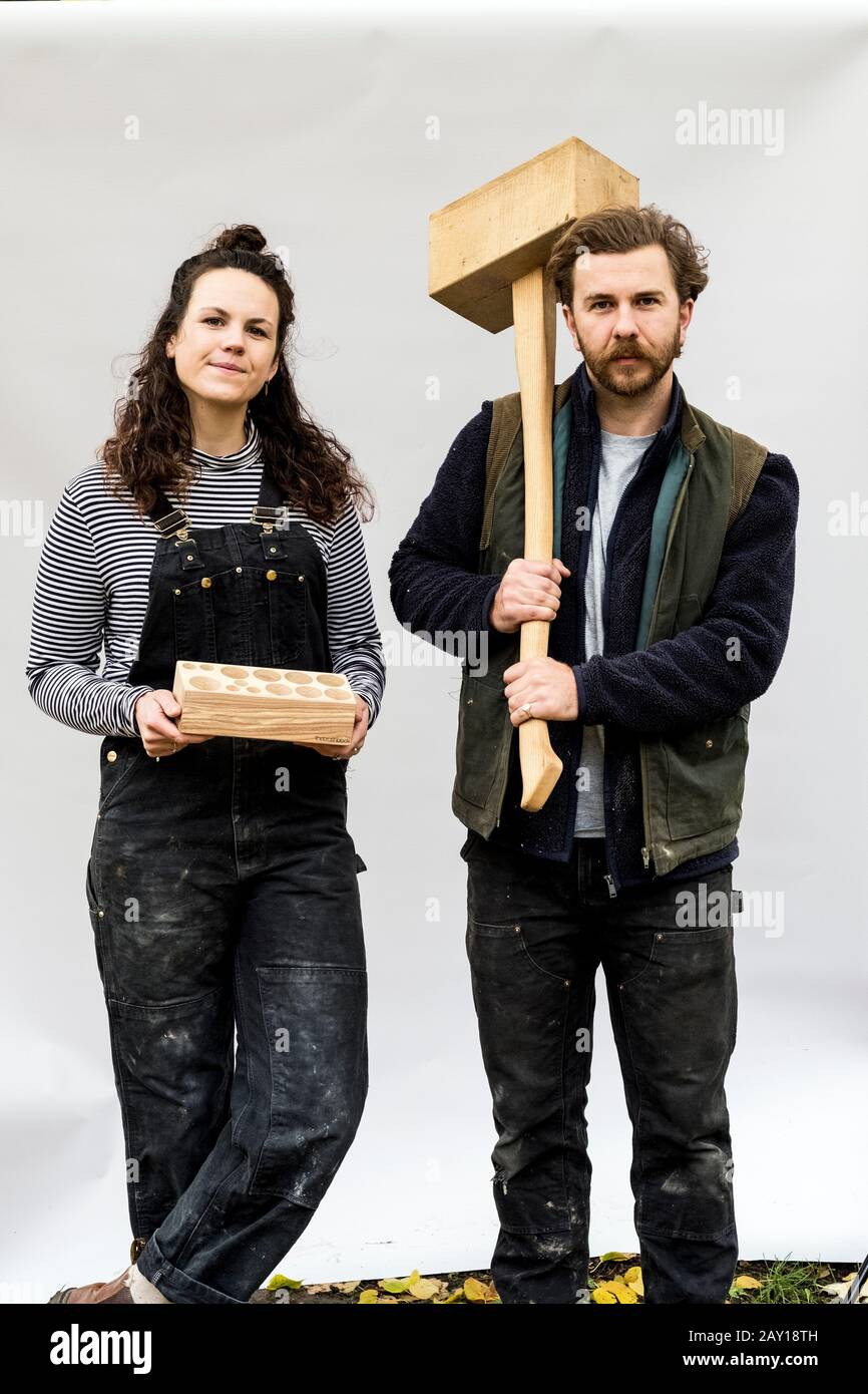 Porträt der Frau und bärtiger Mann, der Holzblöcke vor weißem Hintergrund hält und die Kamera betrachtet. Stockfoto