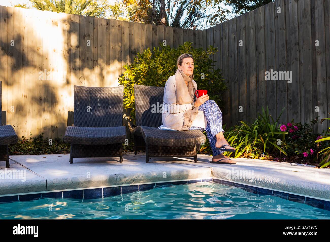 Frau, die auf einer Sonnenliege am Pool sitzt Stockfoto