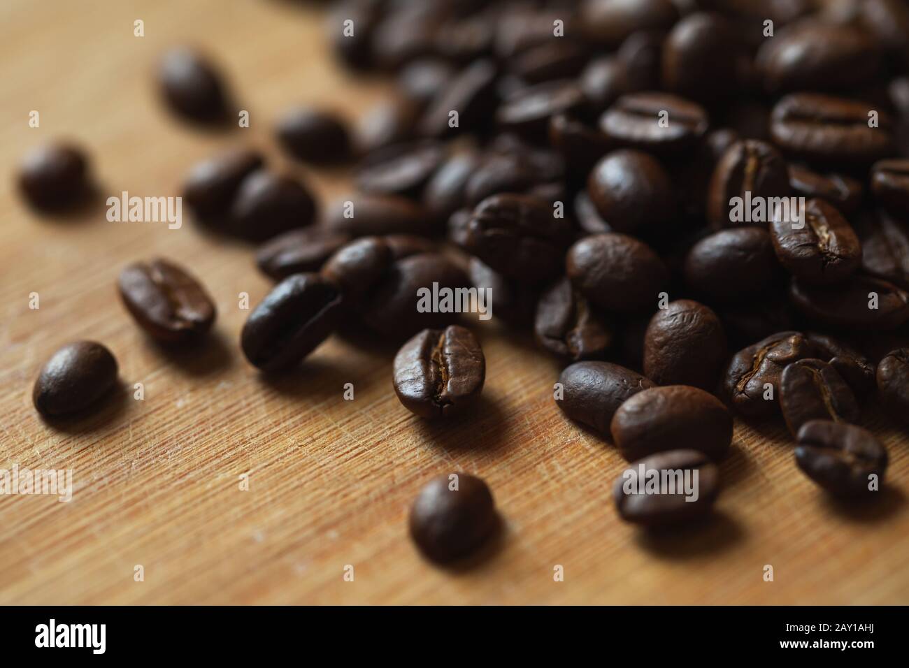 Dunkel geröstete Kaffeebohnen befinden sich auf Holzschreibtisch, Nahaufnahme mit selektivem Fokus Stockfoto