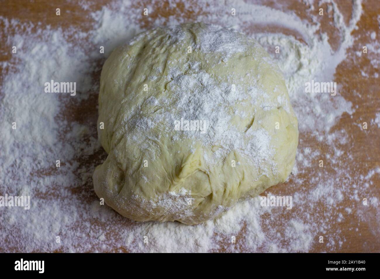 Teigkugel auf dem Tisch mit Mehl bestreut. Teig zum Backen von Desserts oder Pizza. Stockfoto