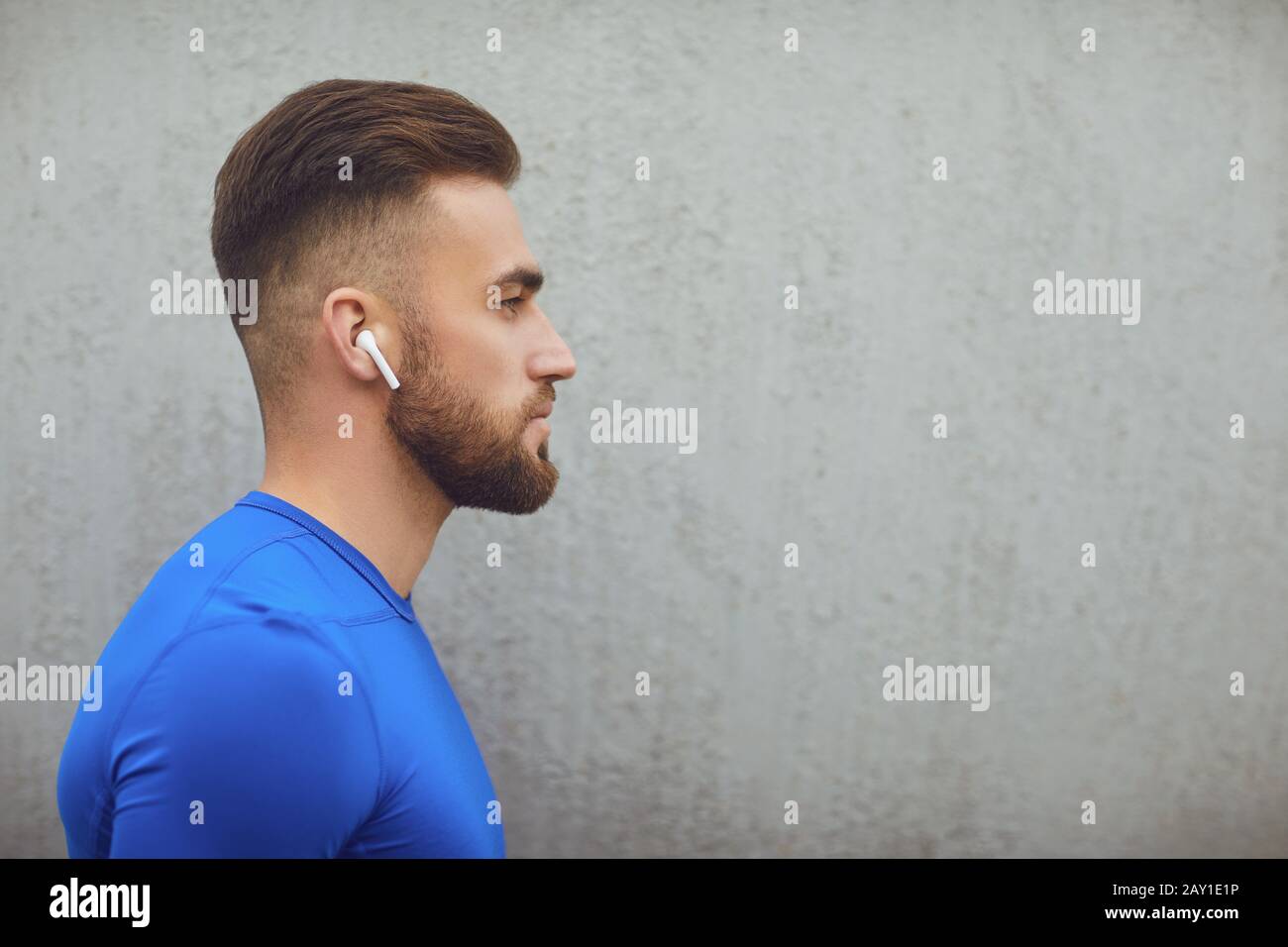 Bärtiger Kerl in Sportkleidung auf grauem Hintergrund. Stockfoto