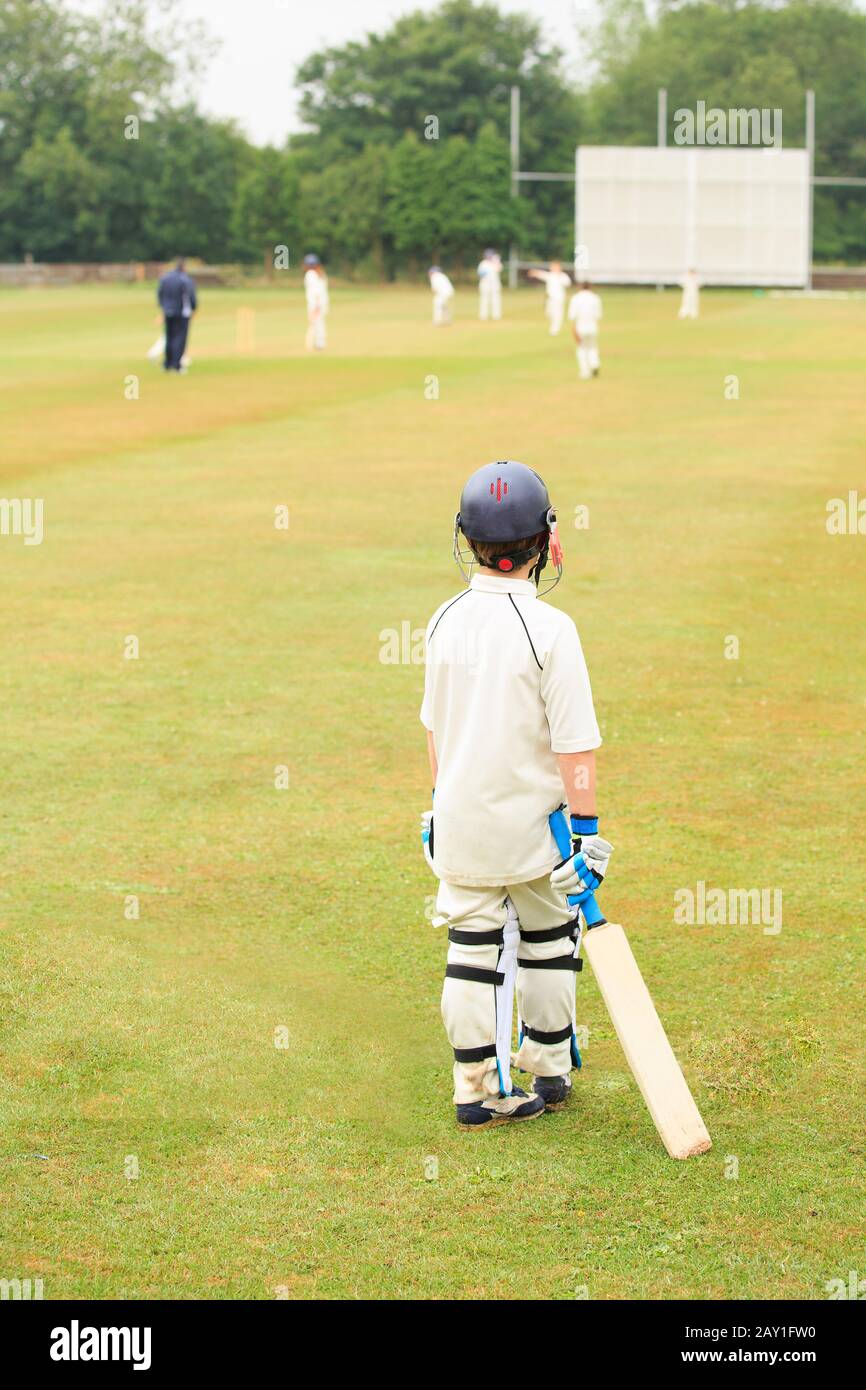 Cricket-Match, Rückansicht eines jungen Jungen, der einen Cricket-Schläger hält, der auf das Spiel wartet. Stockfoto