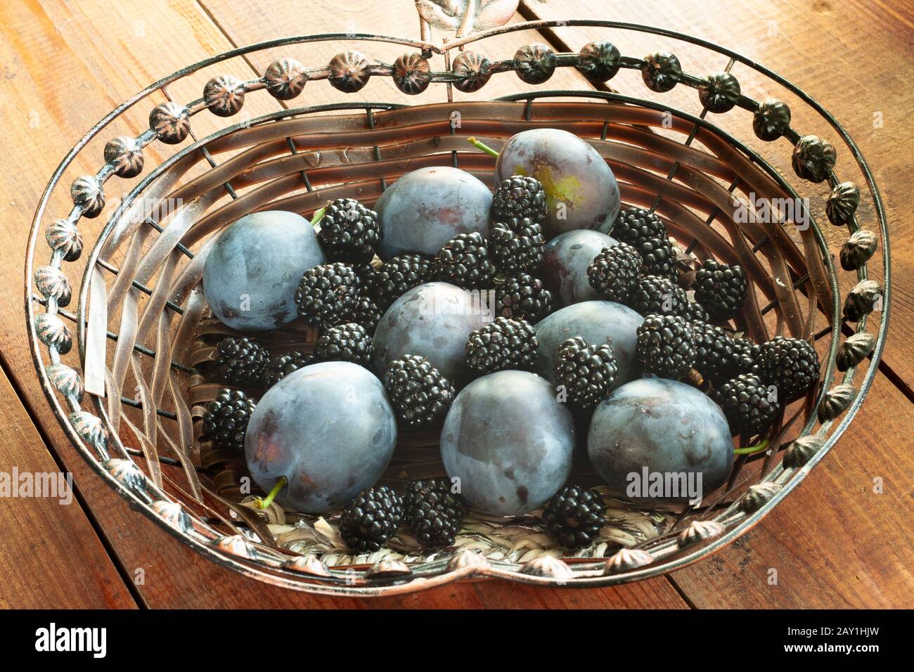 Gemischte Pflaumenfrüchte und Brombeeren in einem Holztisch auf einem Holztisch. Stockfoto