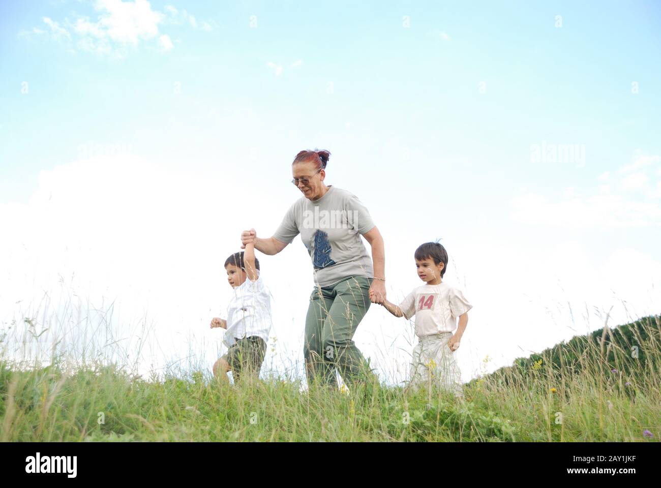 Zwei glückliche Kinder in der Natur mit der Großmutter, die running Stockfoto