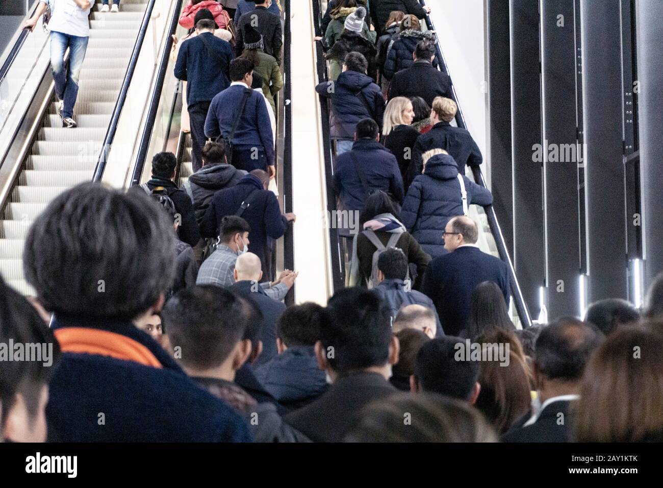 Menschen, die während der Coronovirus-Pandemie auf einer internationalen Messe für Rolltreppen Schlange stehen, einige von ihnen tragen Maske, um sie zu schützen Stockfoto