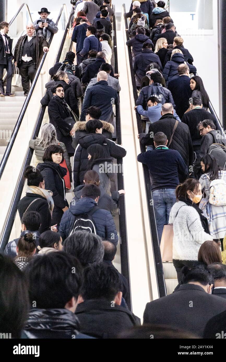 Menschen, die während der Coronovirus-Pandemie auf einer internationalen Messe für Rolltreppen Schlange stehen, einige von ihnen tragen Maske, um sie zu schützen Stockfoto