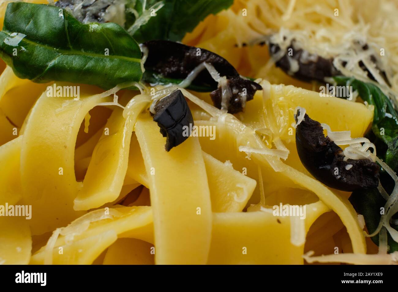 Makrofoto mit geringer Schärfe von Pasta mit Parmesan, gehackten Oliven und Basilikum Stockfoto