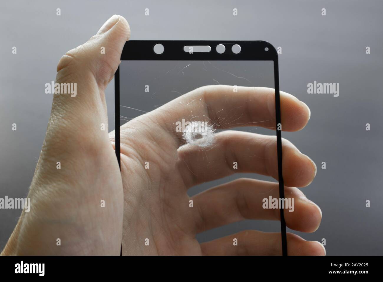 Zerbrochenes Schutzglas des Smartphones mit Rissen in der Hand auf schwarzem Hintergrund. Stockfoto
