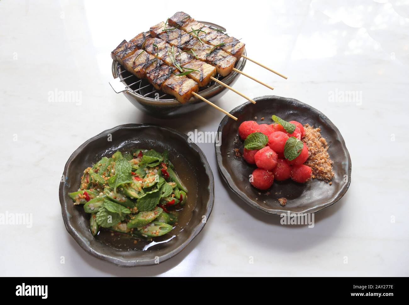 Thai-Food zeichnet sich durch leicht zubereitete Gerichte mit starken aromatischen Komponenten und einem würzigen Rand aus. Es gibt Satay, Okra und Wassermelone. Stockfoto