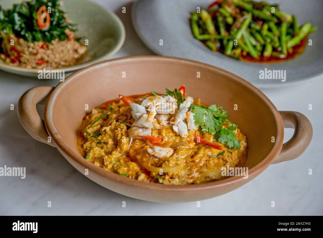 Thai-Food zeichnet sich durch leicht zubereitete Gerichte mit starken aromatischen Komponenten und einem würzigen Rand aus. Hier ist ein Krabbencurry, lange Bohnen und Schweinefleisch. Stockfoto