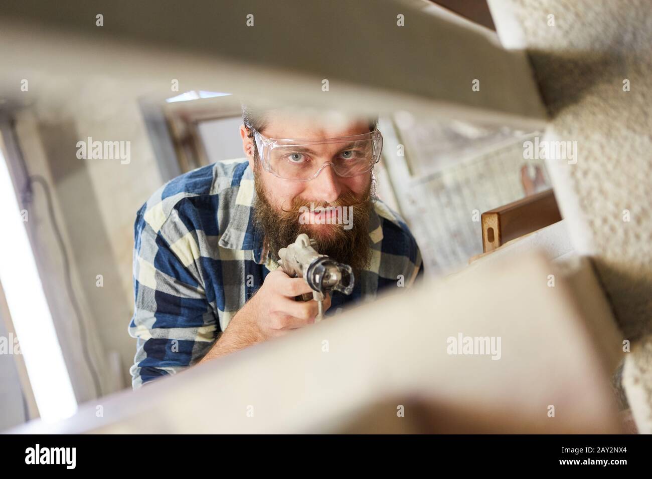 Maler beim Lackieren von Möbeln mit Holzglasur in der Zimmerei die Spritzpistole verwenden Stockfoto