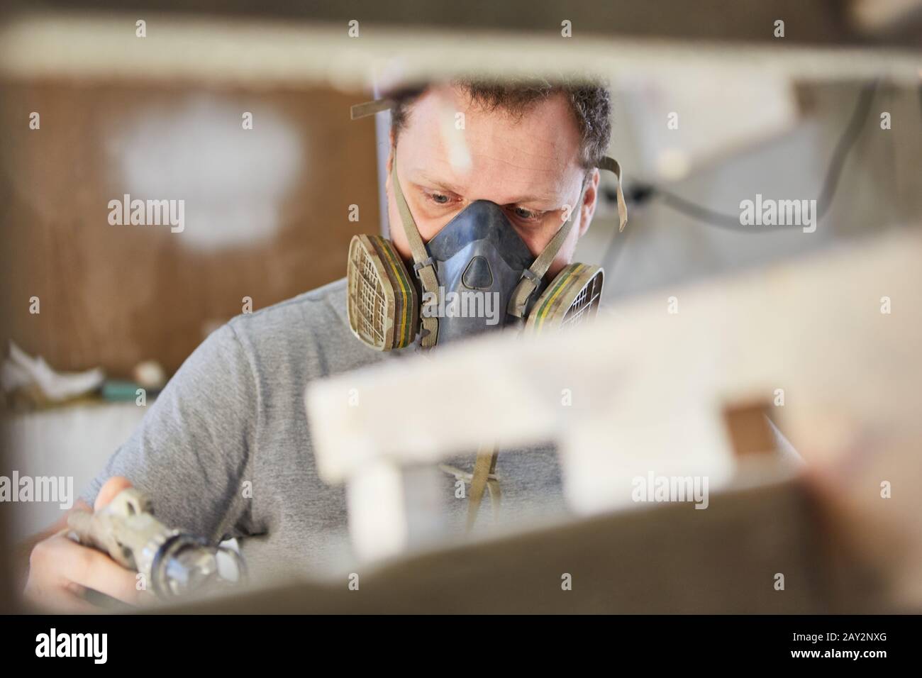 Mann als Maler mit Atemschutzmaskenfärbung oder Holzmalen Stockfoto