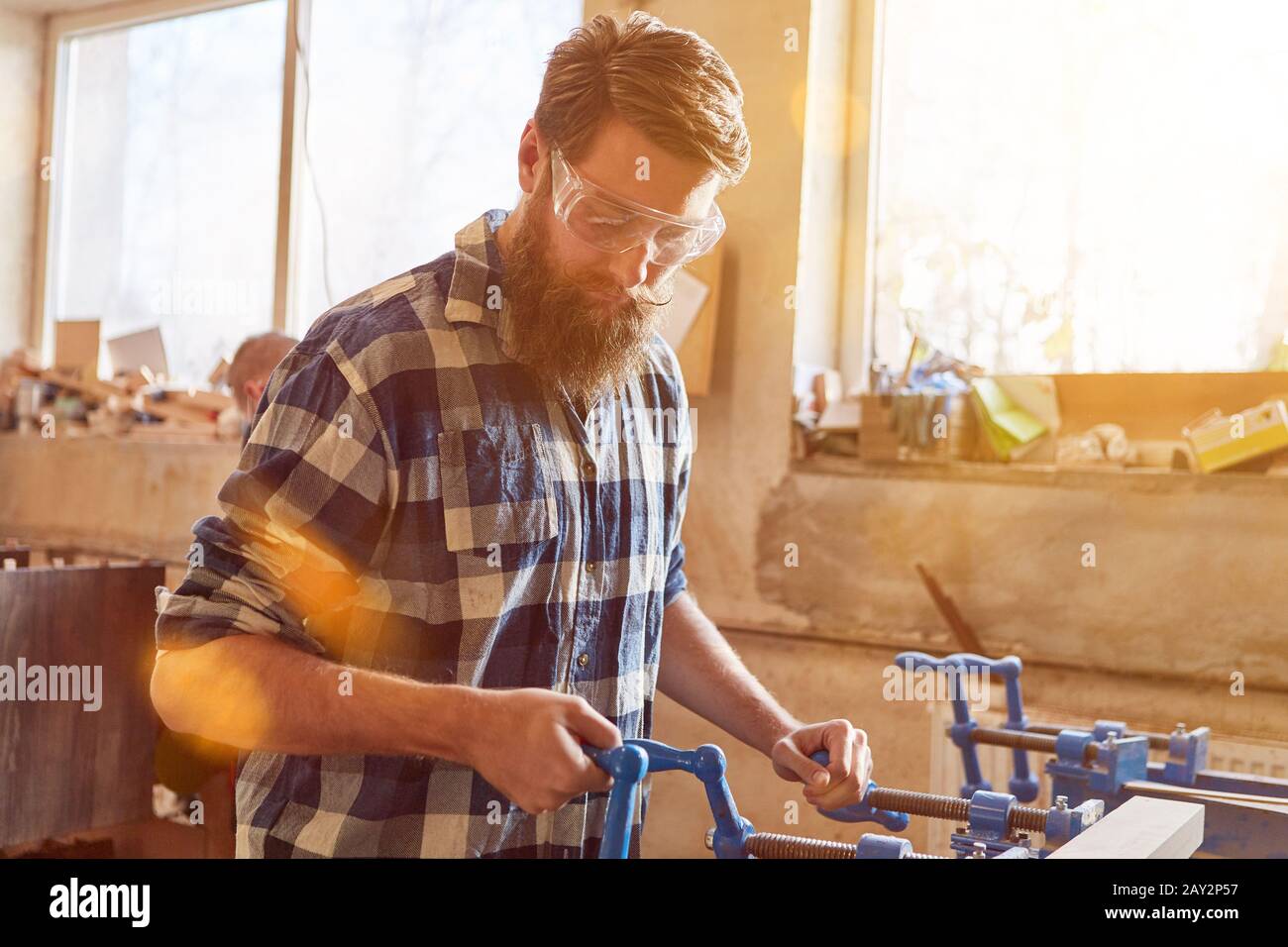 Tischler mit Schutzbrille arbeitet auf einem Schraubstock in der Zimmerei Stockfoto