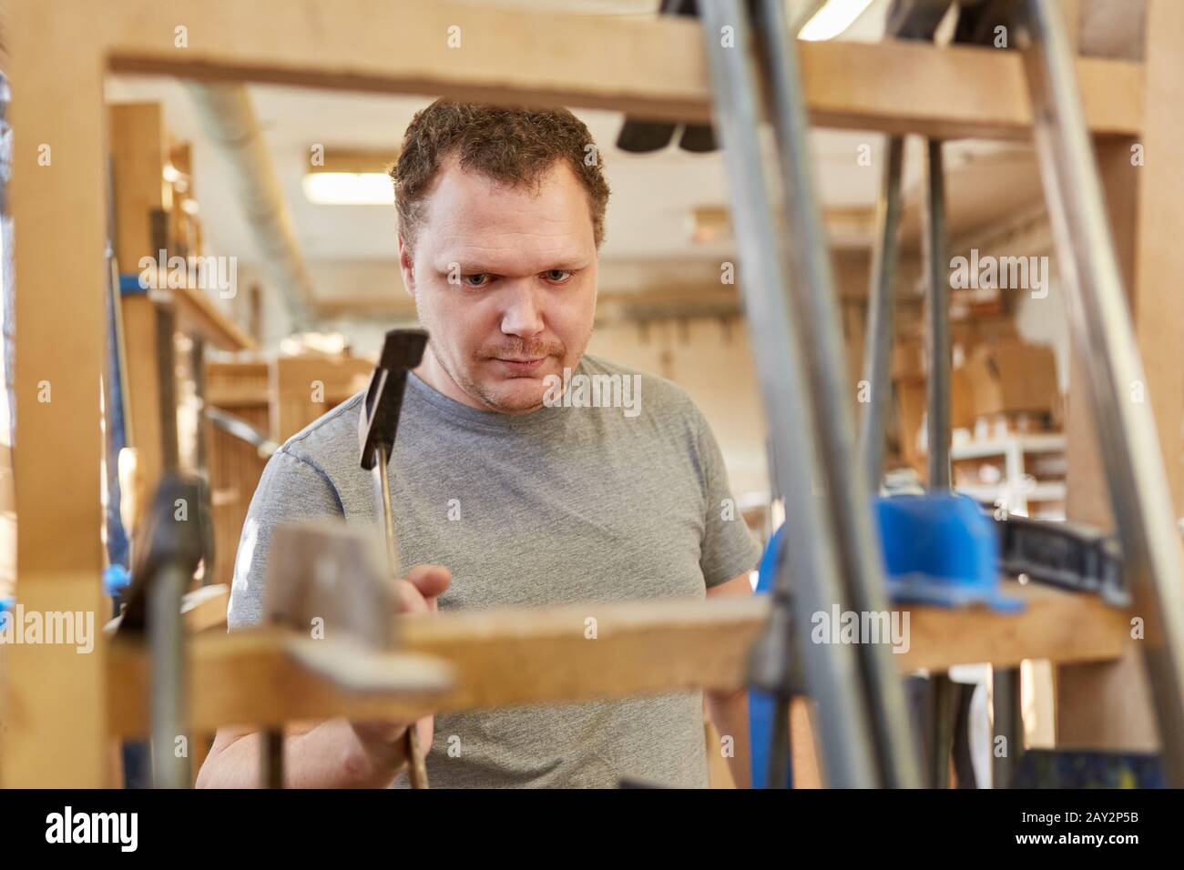 Tischlerlehrling arbeitet mit Schraubklemmen in der Zimmerei der Möbelherstellung Stockfoto