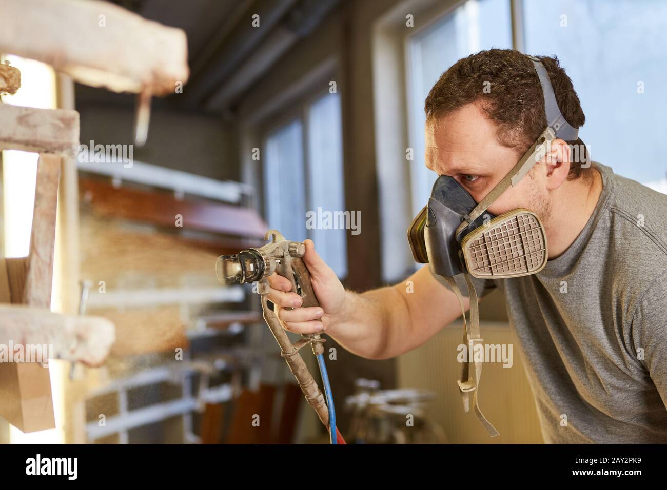 Varnisher lackiert Holz mit Gesichtsmaske und Brille im Zimmerei Stockfoto