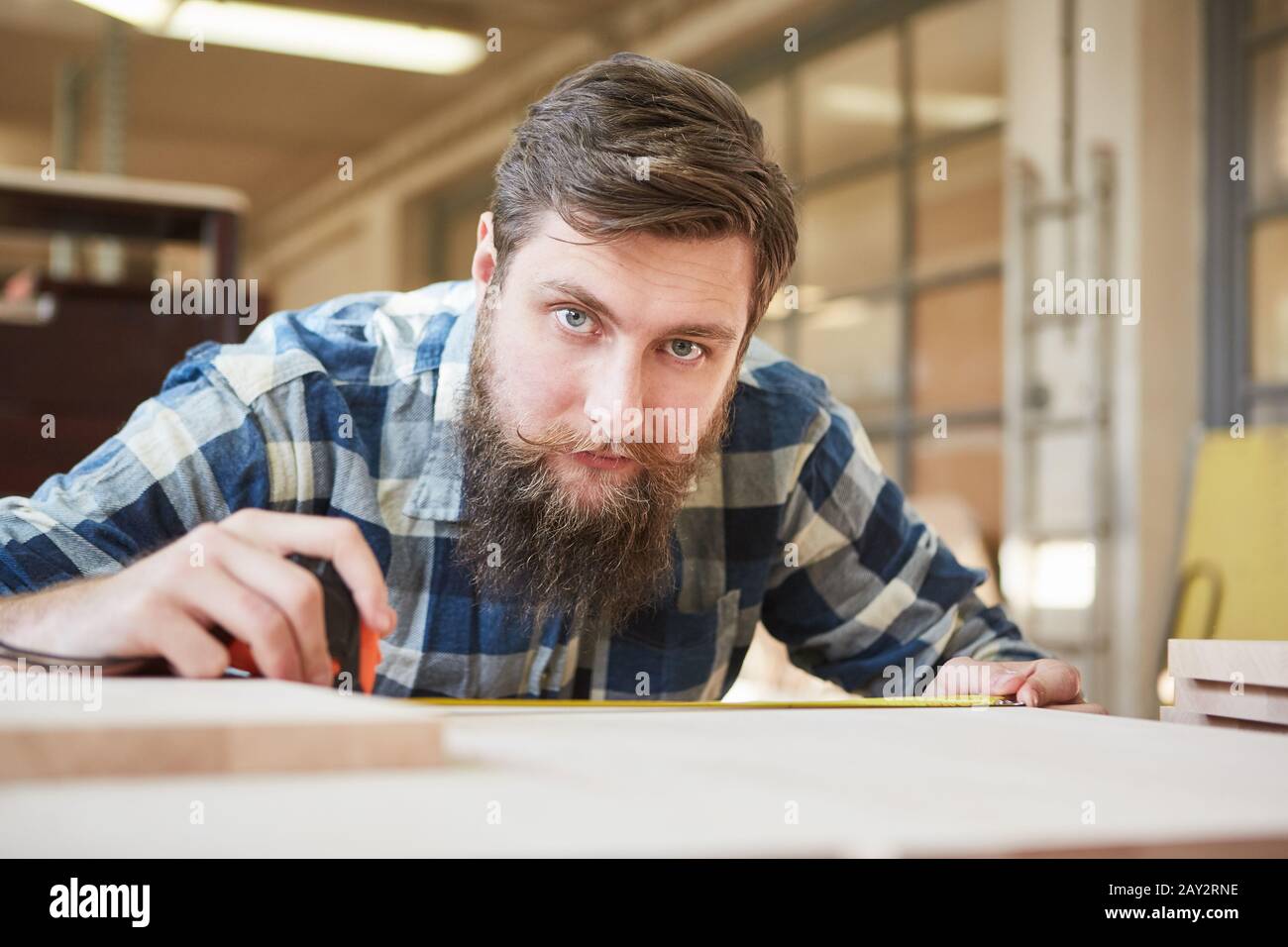 Hipper Mann mit Bart als Tischlerlehrling Bauregale in Zimmerei Stockfoto