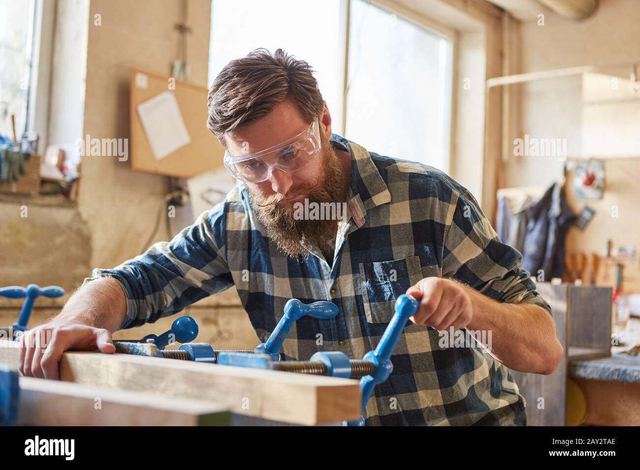 Tischler mit Schutzbrille arbeitet mit Holz auf dem Schraubstock in der Zimmerei Stockfoto