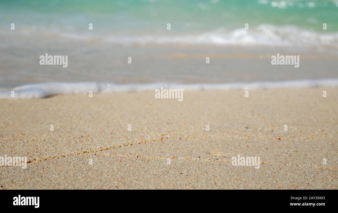 Sanfte Welle des blauen Ozeans am weißen sandigen Strand. Sommerlicher Hintergrund. Stockfoto