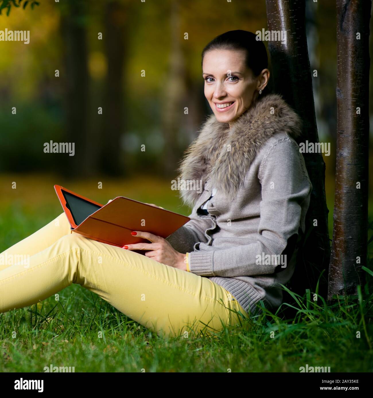 Mode-Frau mit einem Tabletcomputer außerhalb in Abend-park Stockfoto