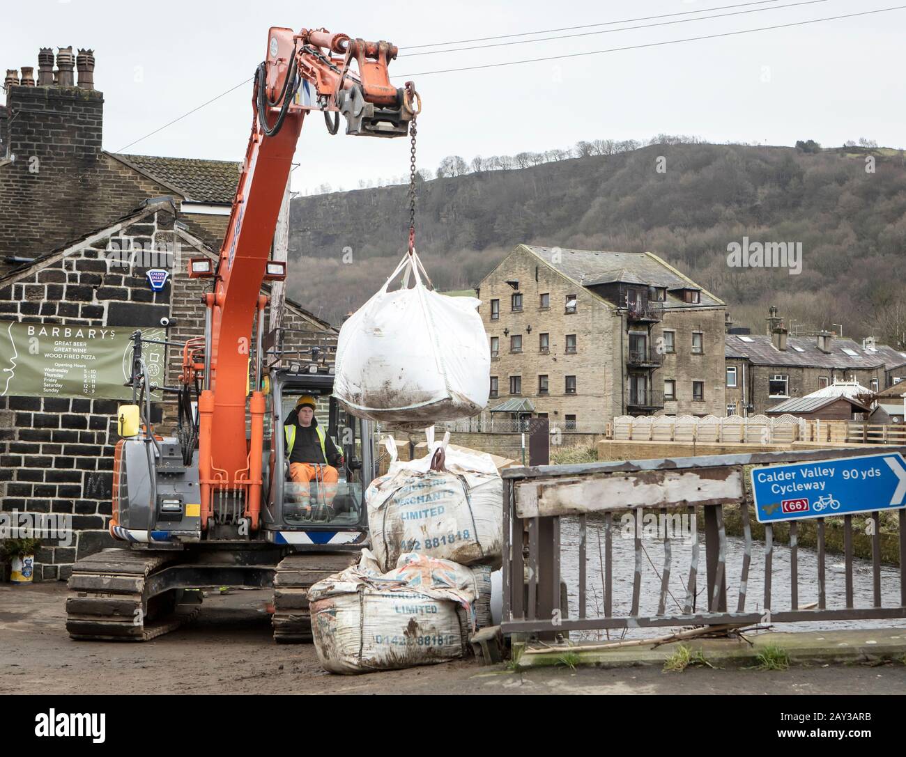 Arbeiter bauen in Mytholmroyd im oberen Calder Valley in West Yorkshire vor dem Sturm Dennis Hochwasserschutzanlagen auf. Stockfoto