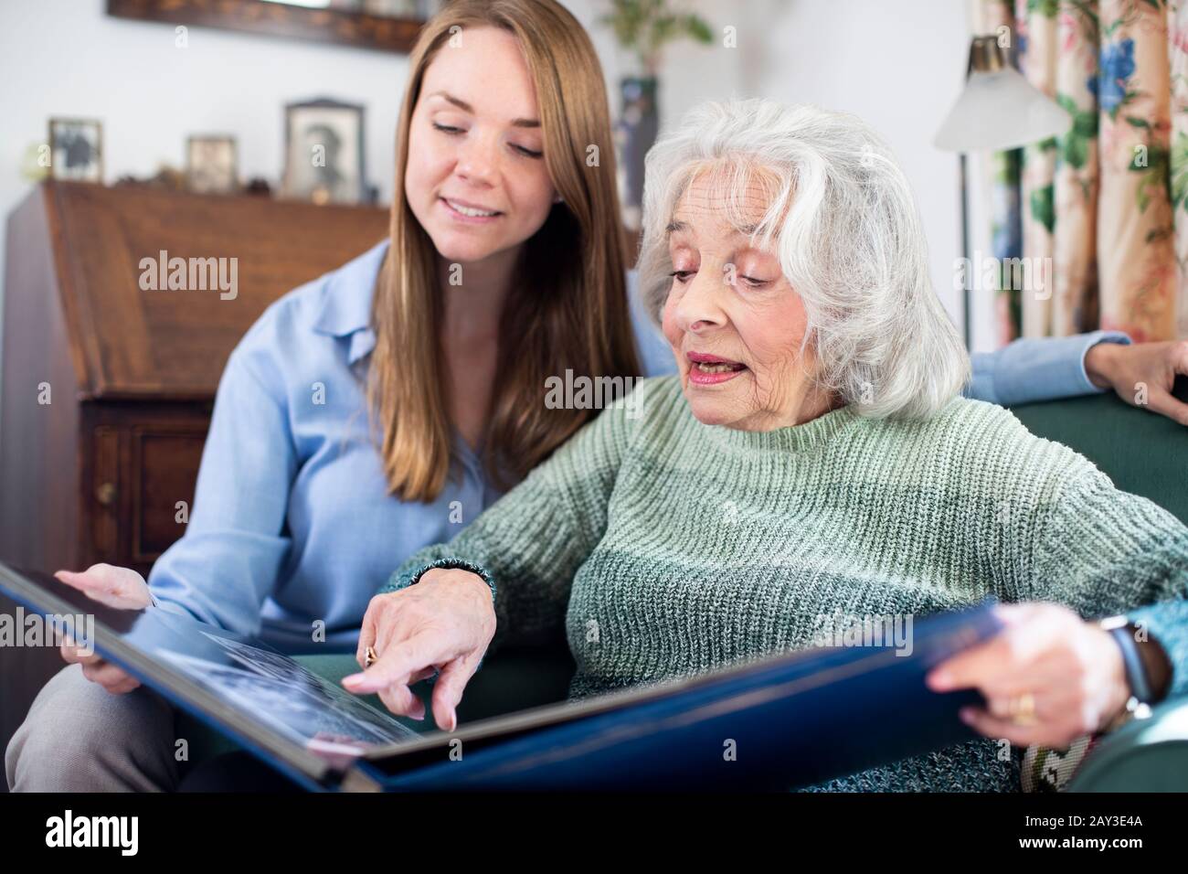Großmutter an Fotoalbum mit Erwachsenen Enkelin Suchen Stockfoto