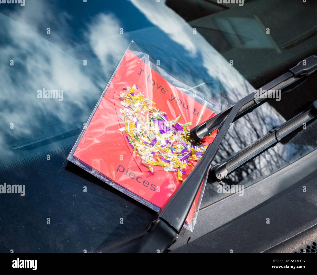 Romantische Überraschung. Hausgemachte Valentinskarte "I love you to pieces", unter den Scheibenwischern einer Autoscheibe, Nottinghamshire, England, Großbritannien Stockfoto