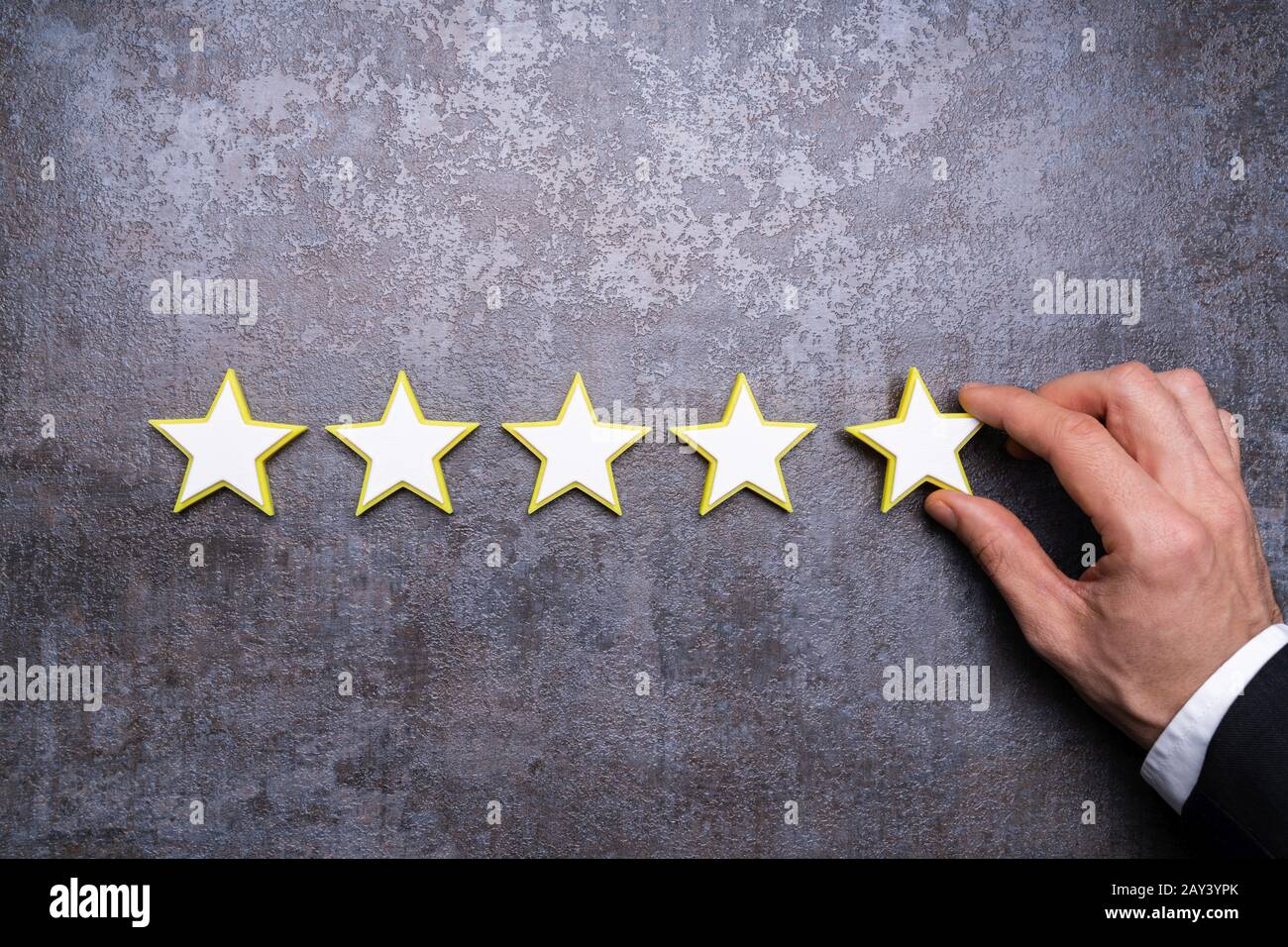 Die Hand der Person, Die Das Symbol Für Die Bewertung Von Fünf Sternen Am Schreibtisch bildet Stockfoto