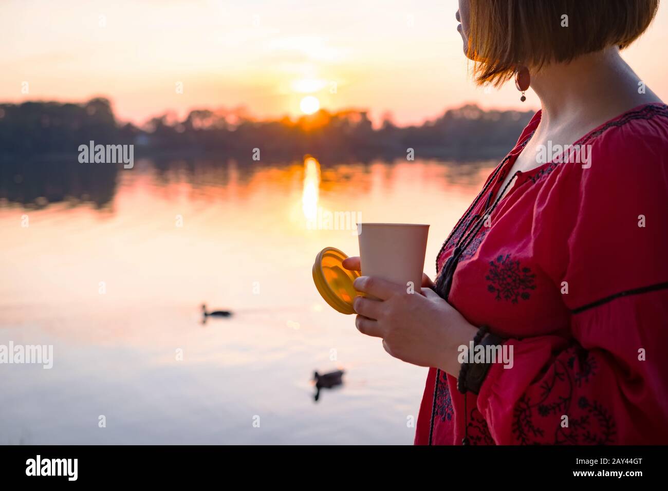 Eine kurzhaarige Frau, die eine Bambusbecher mit Kaffee hält Stockfoto