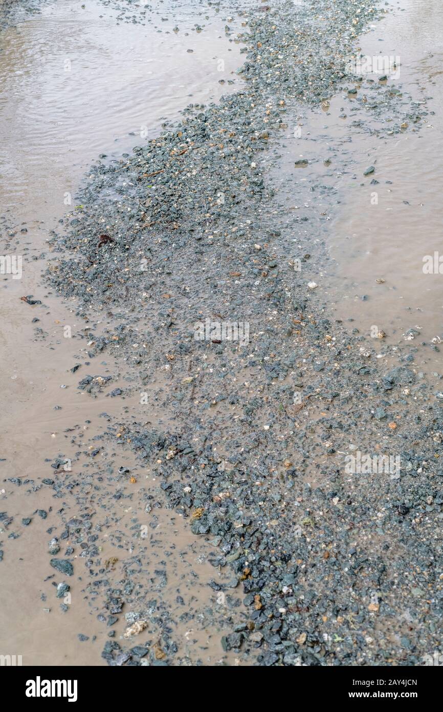 Licht, das von Wasserpfützen auf Landwegen reflektiert wird. Für Schlagoleinbrüche, Wasserpfütze, Wasserspiegelung, holprige Oberfläche, unebene Oberfläche, schlechter Zustand. Stockfoto