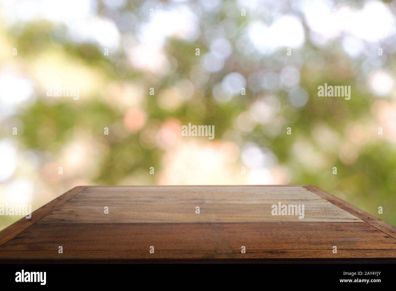 Leerer Holztisch vor abstraktem, verschwommenem grünem Bokeh-Licht aus Garten und Naturlicht. Für Montage Produktanzeige oder Design Key Vis Stockfoto