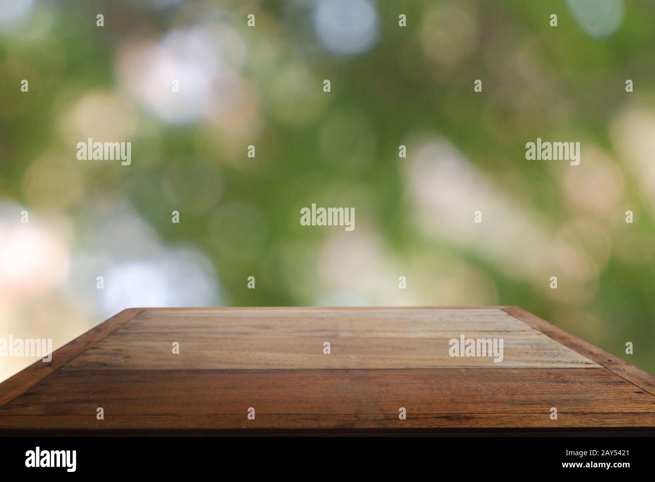 Leerer Holztisch vor abstraktem, verschwommenem grünem Bokeh-Licht aus Garten und Naturlicht. Für Montage Produktanzeige oder Design Key Vis Stockfoto