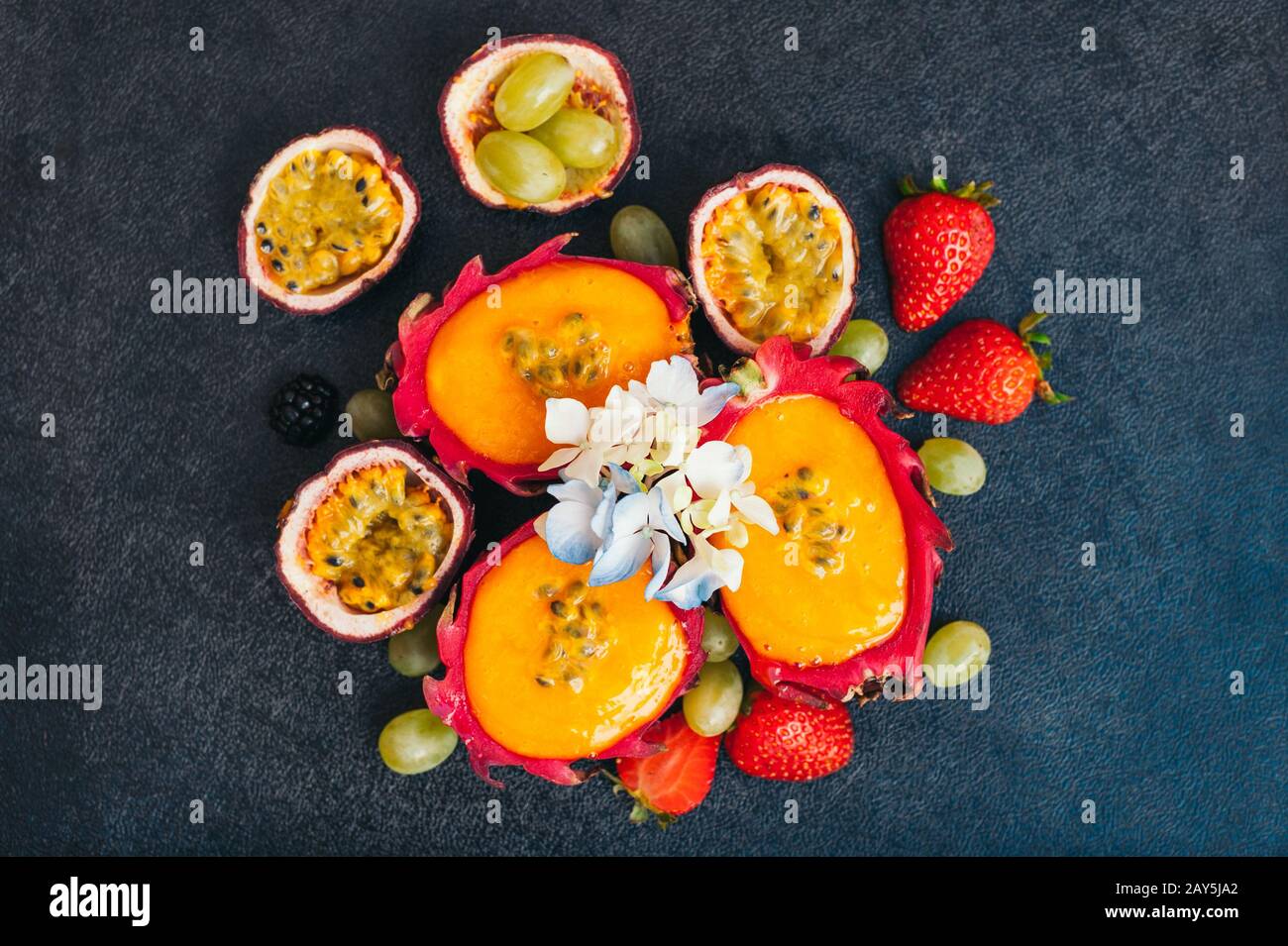 Scheiben Drachenfrucht, rote reife Erdbeere und Trauben auf dunklem Grund. Frisches Obst für veganten Salat. Ernährung und Vitamine Konz Stockfoto