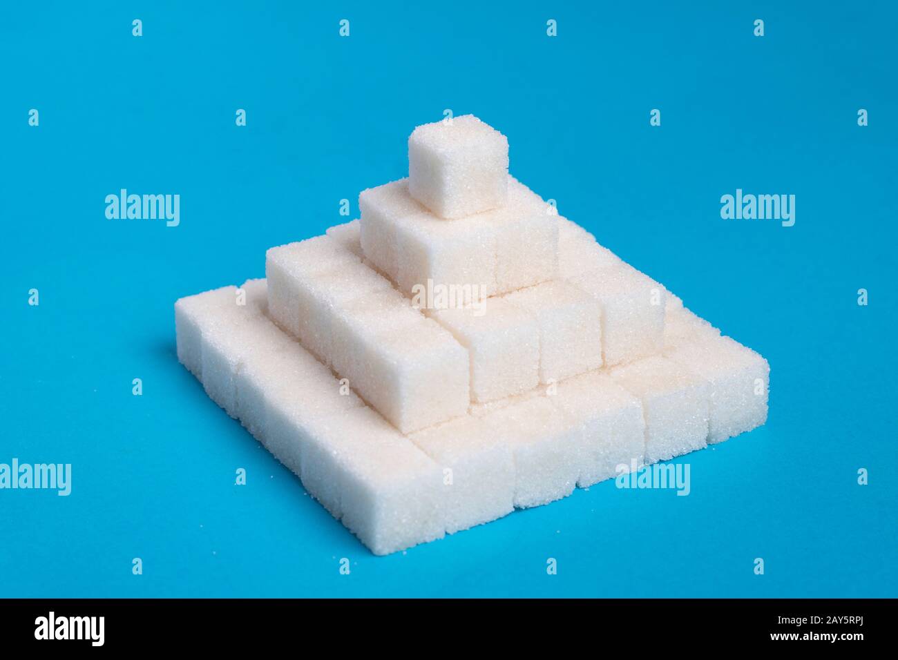 Zuckerwürfelpyramide auf blauem Hintergrund, kreative Idee für Lebensmittel Stockfoto