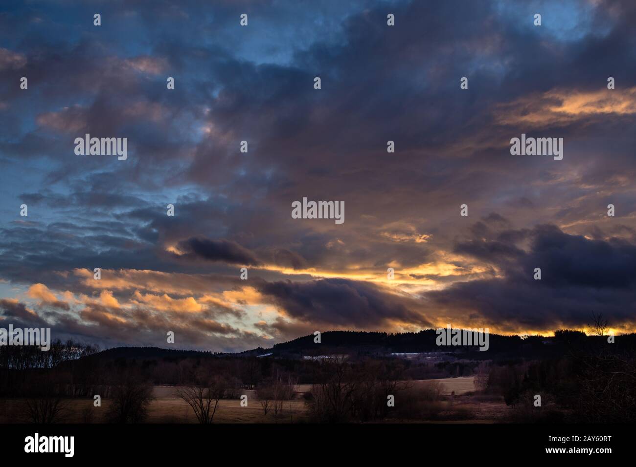 Wunderschöner Sonnenuntergang - roter Himmel über der Hügellandschaft, blauer Himmel mit orangefarbenen Wolken Stockfoto