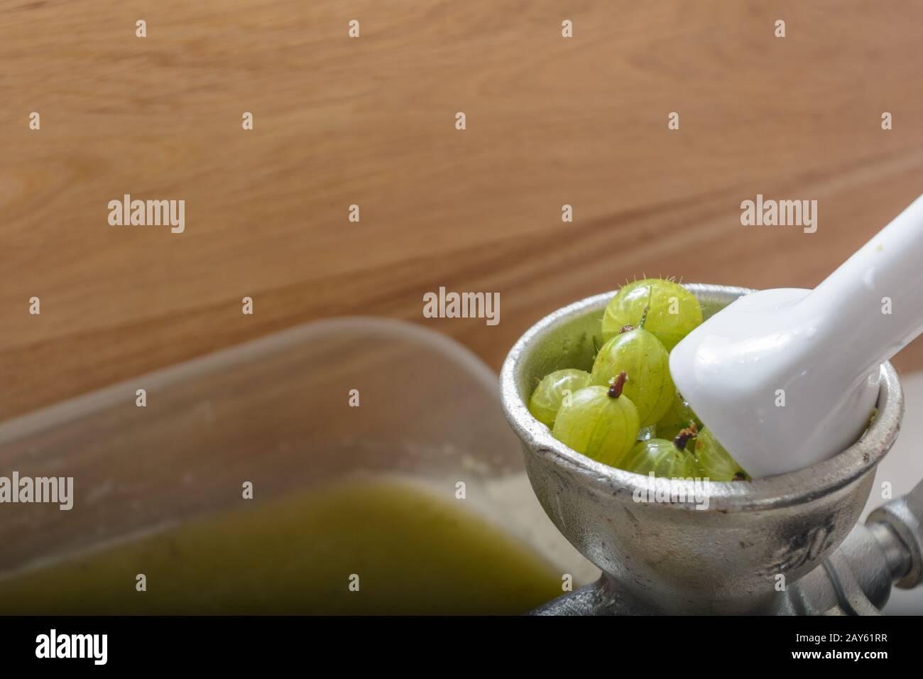 Grüne Stachelbeeren werden in einer Fruchtpresse gepresst - Nahaufnahme Stockfoto