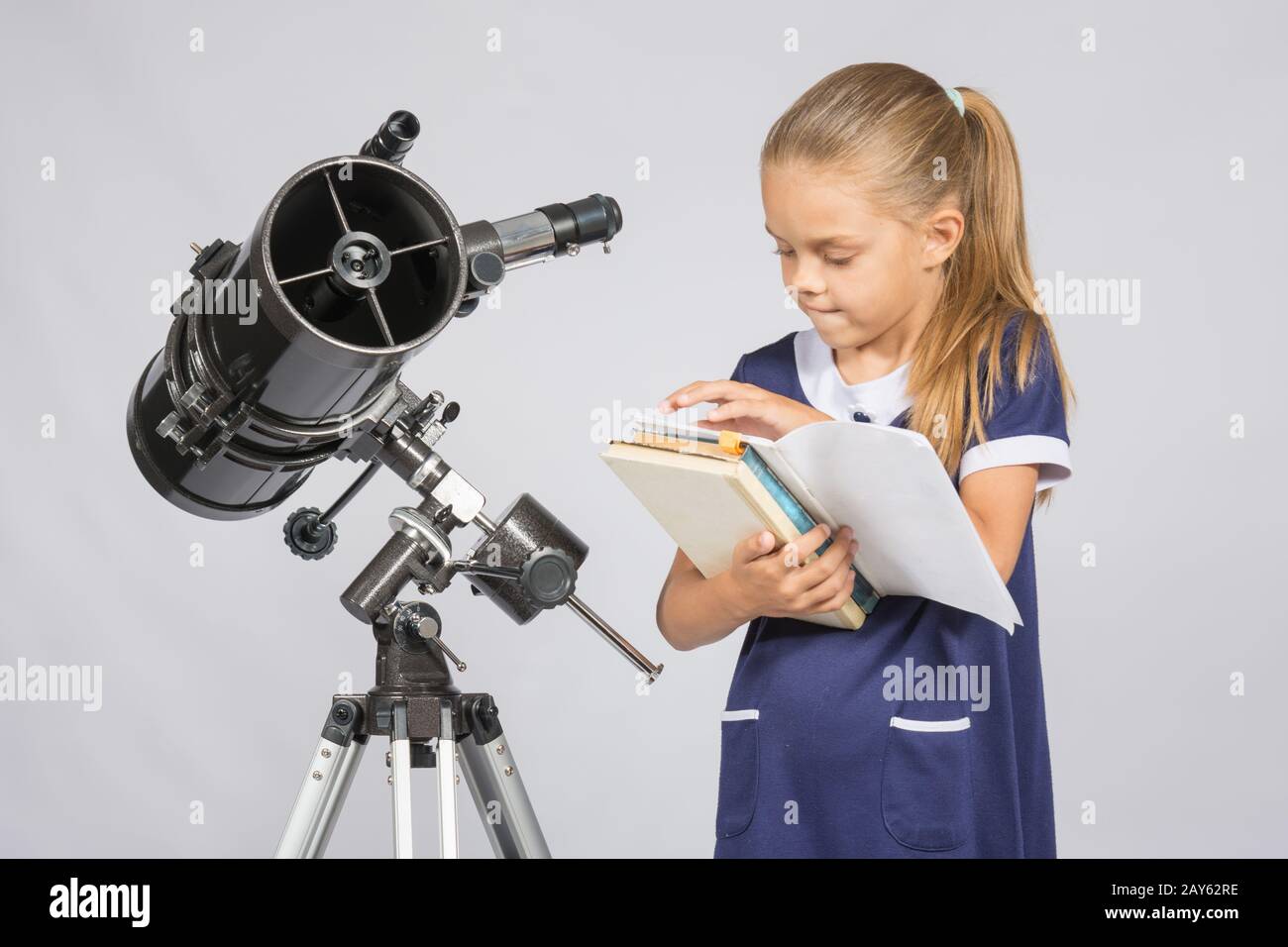 Schulmädchen-Astronom Bücher durchblättern, die richtige Informationen am Stand des Teleskops zu finden Stockfoto