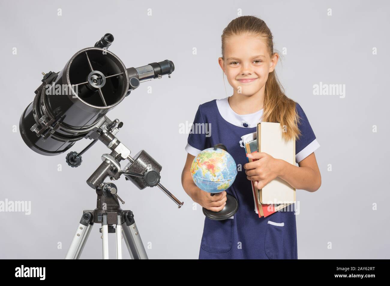 Mädchen-Astronom ist ein Teleskop mit einem Globus und Bücher in den Händen Stockfoto