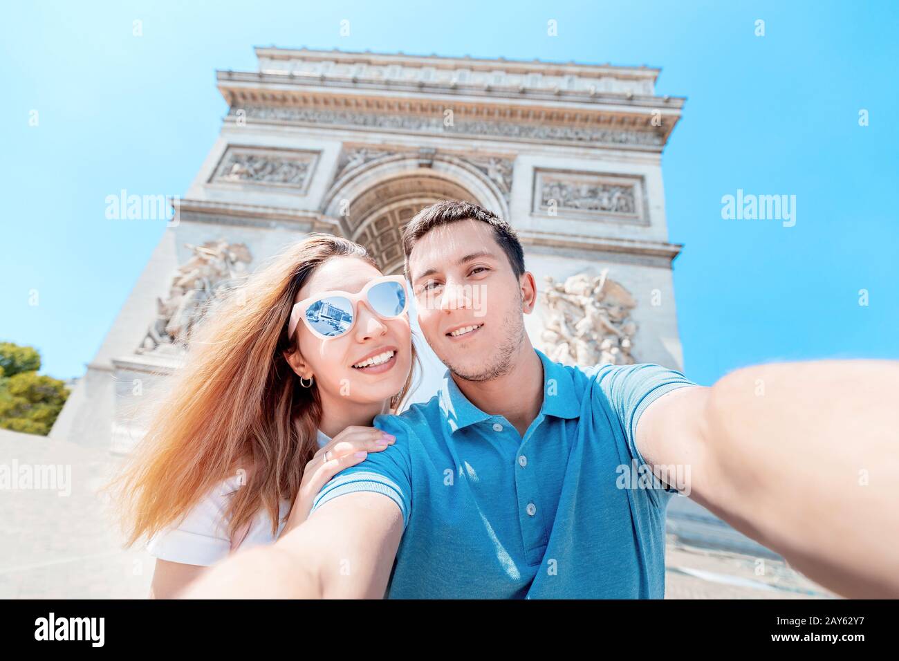 Ein glücklicher Mann und ein Mädchen umarmen sich und machen ein selfie-foto gegen den Triumphbogen in Paris. Flitterwochen und eine gemeinsame Reise in Frankreich Stockfoto
