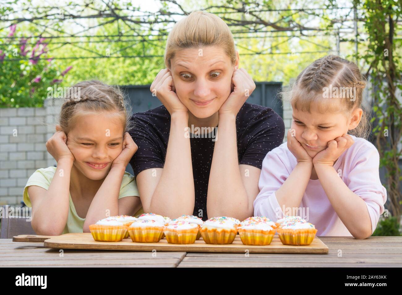 Mutter und zwei Töchter mit verschiedenen lustigen Emotion Blick auf Ostern cupcakes Stockfoto